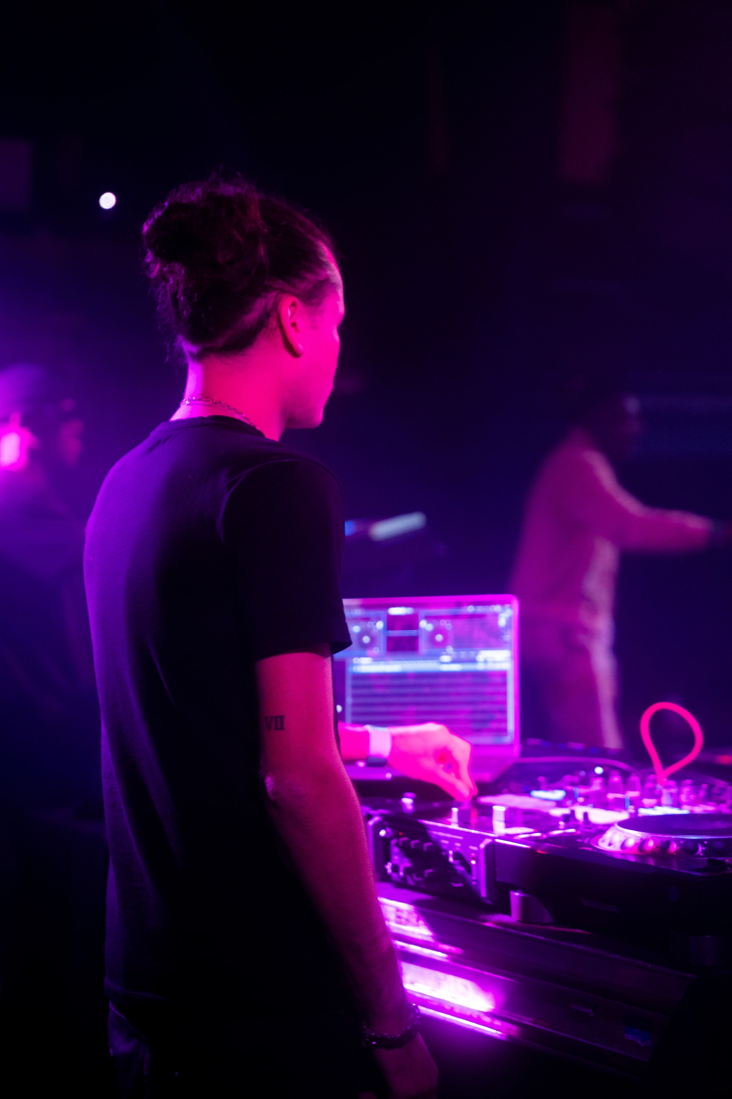 Le DJ de dos derrière ses platines éclairées de violet