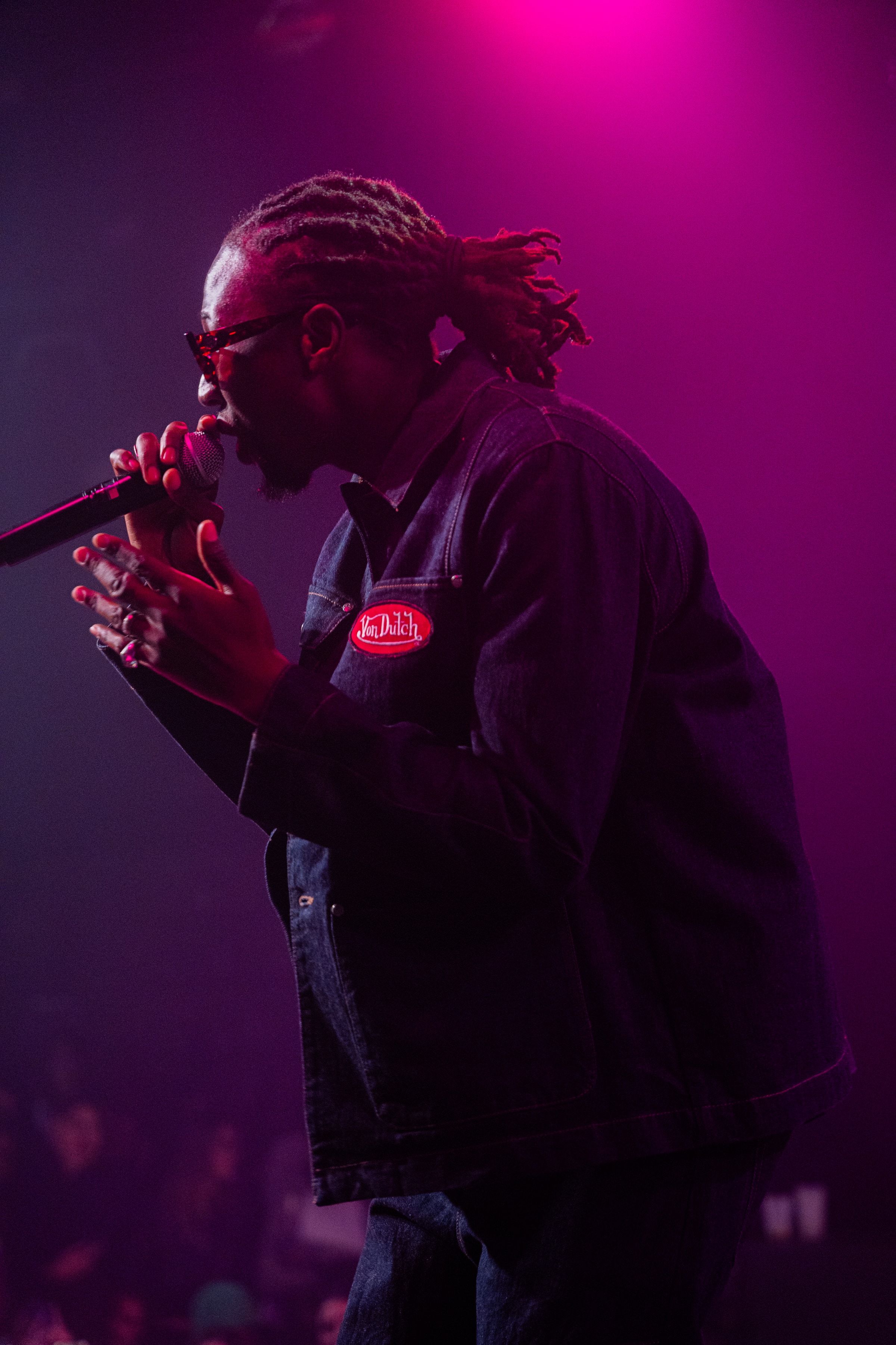Le rappeur de profil, micro à la bouche, baigné de rose