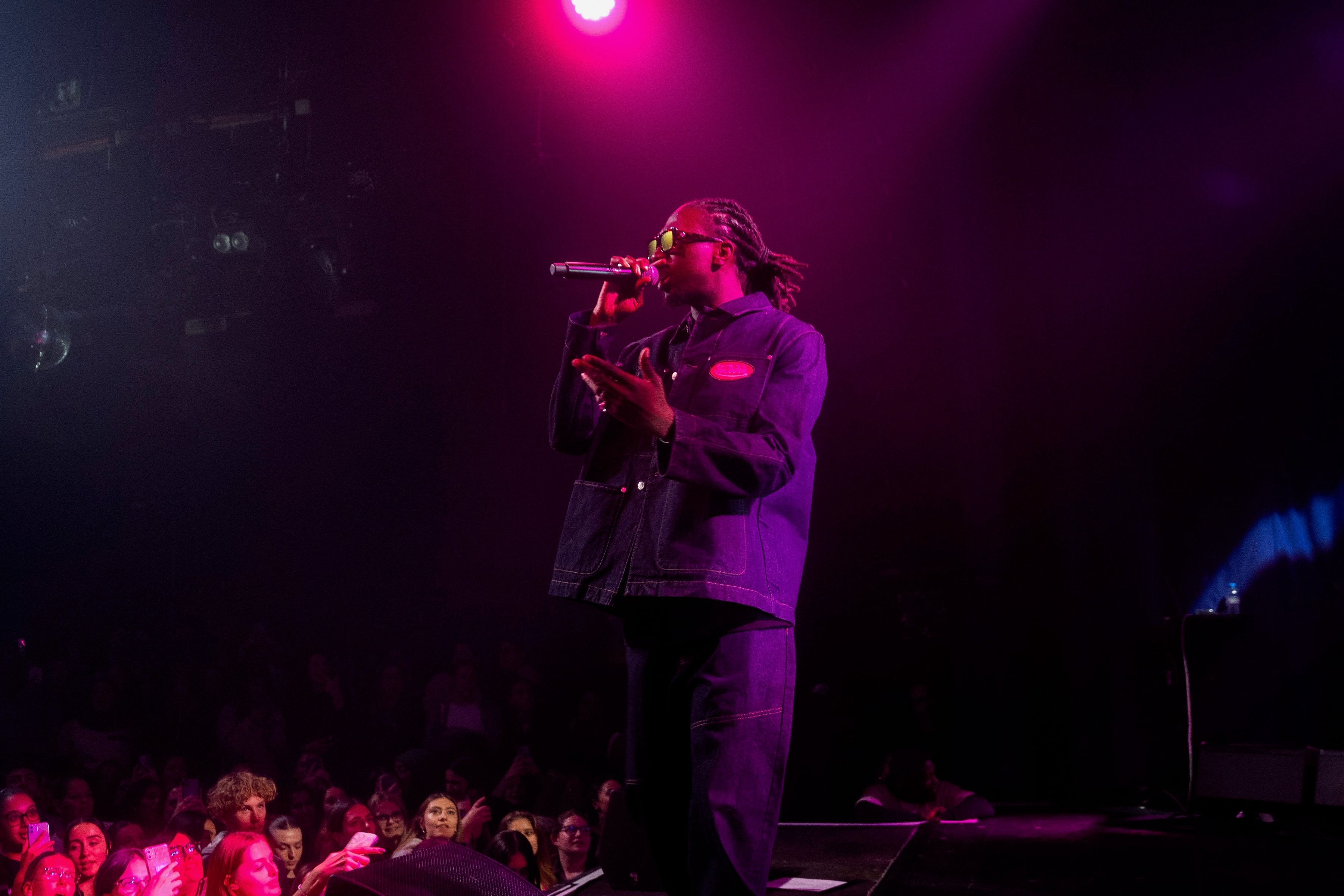 Le rappeur chante sur la scène sombre, la foule au premier plan