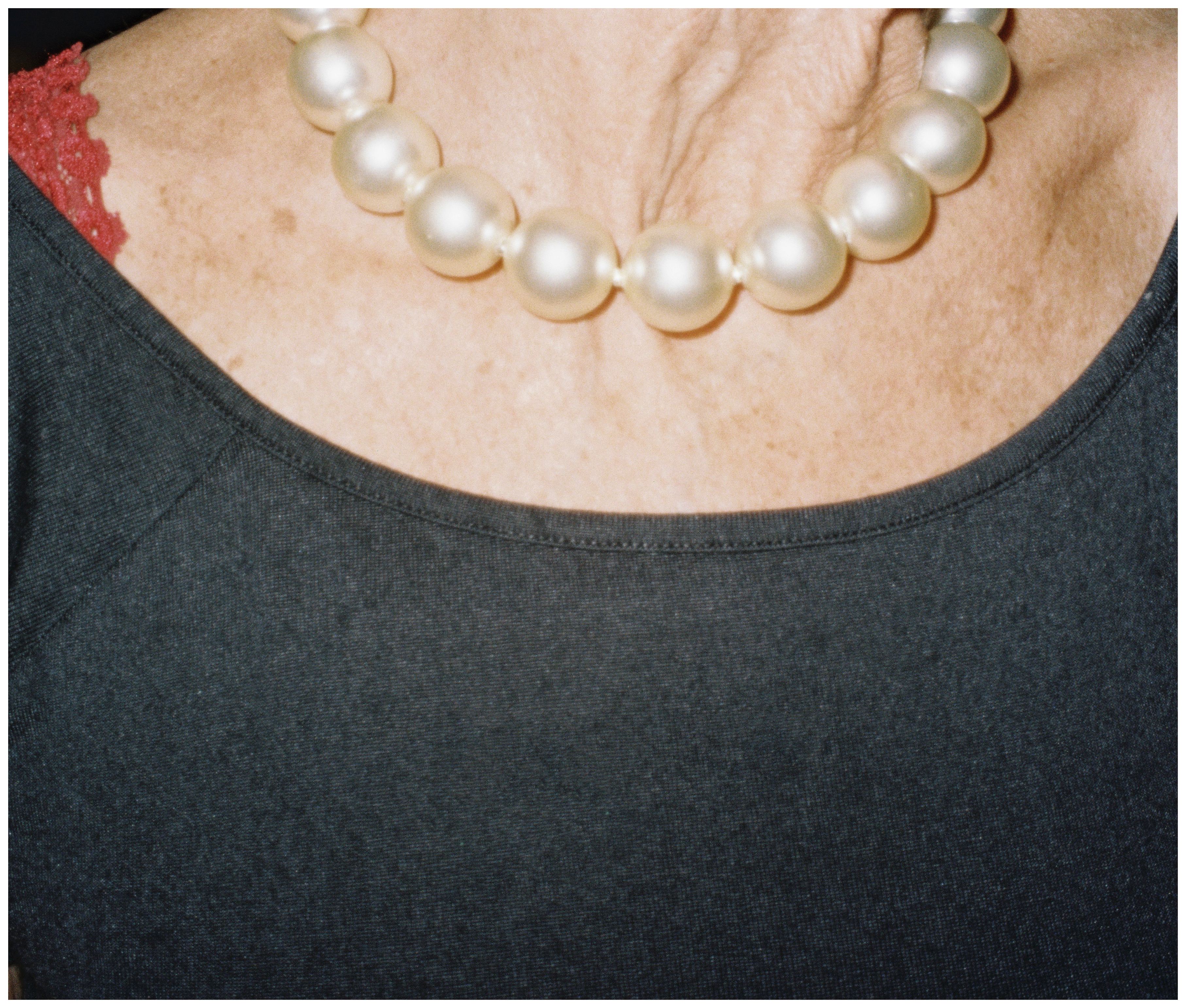Gros plan sur un collier de grosses perles posé sur un haut noir